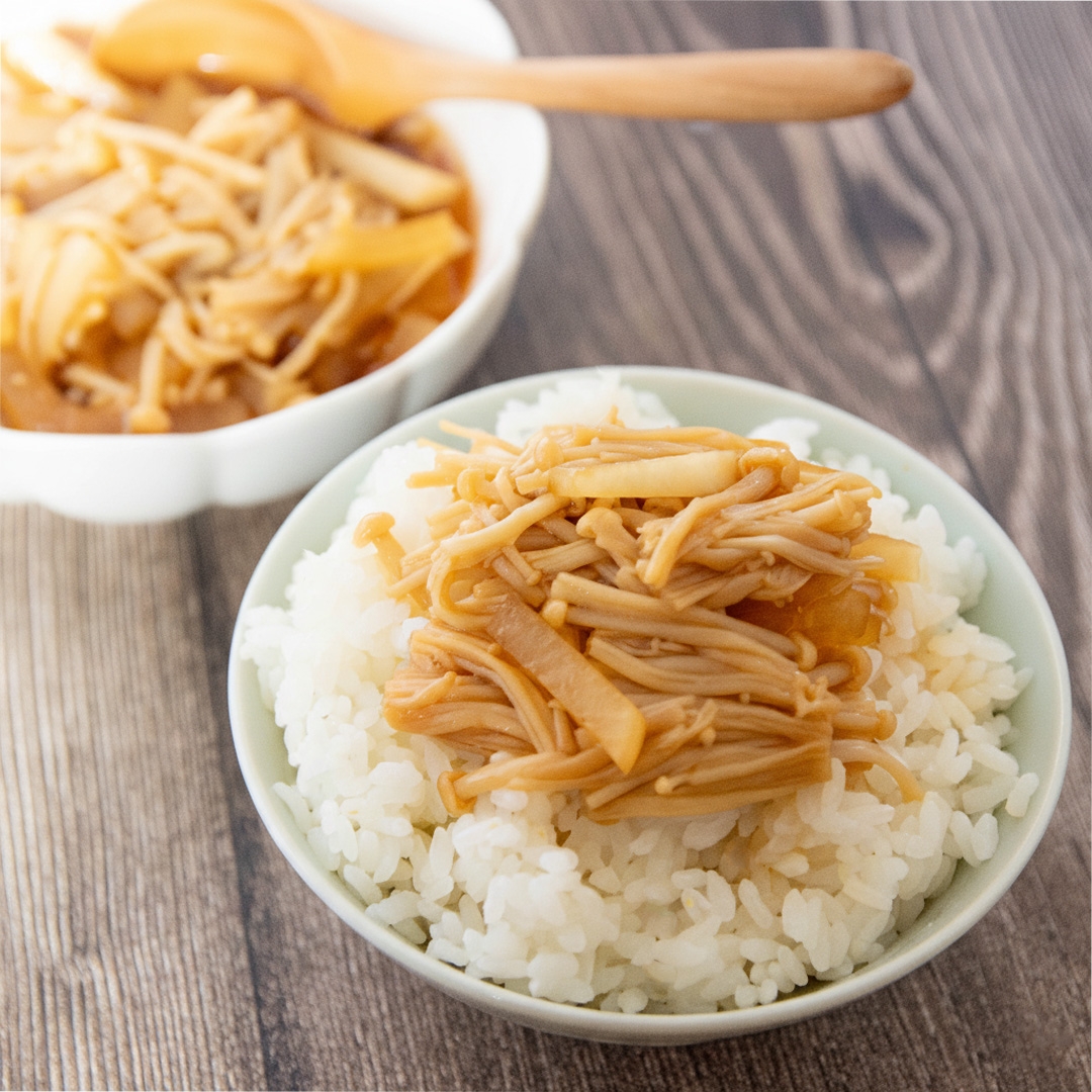 なめたけがトッピングされたご飯の丼がテーブルに置かれている。