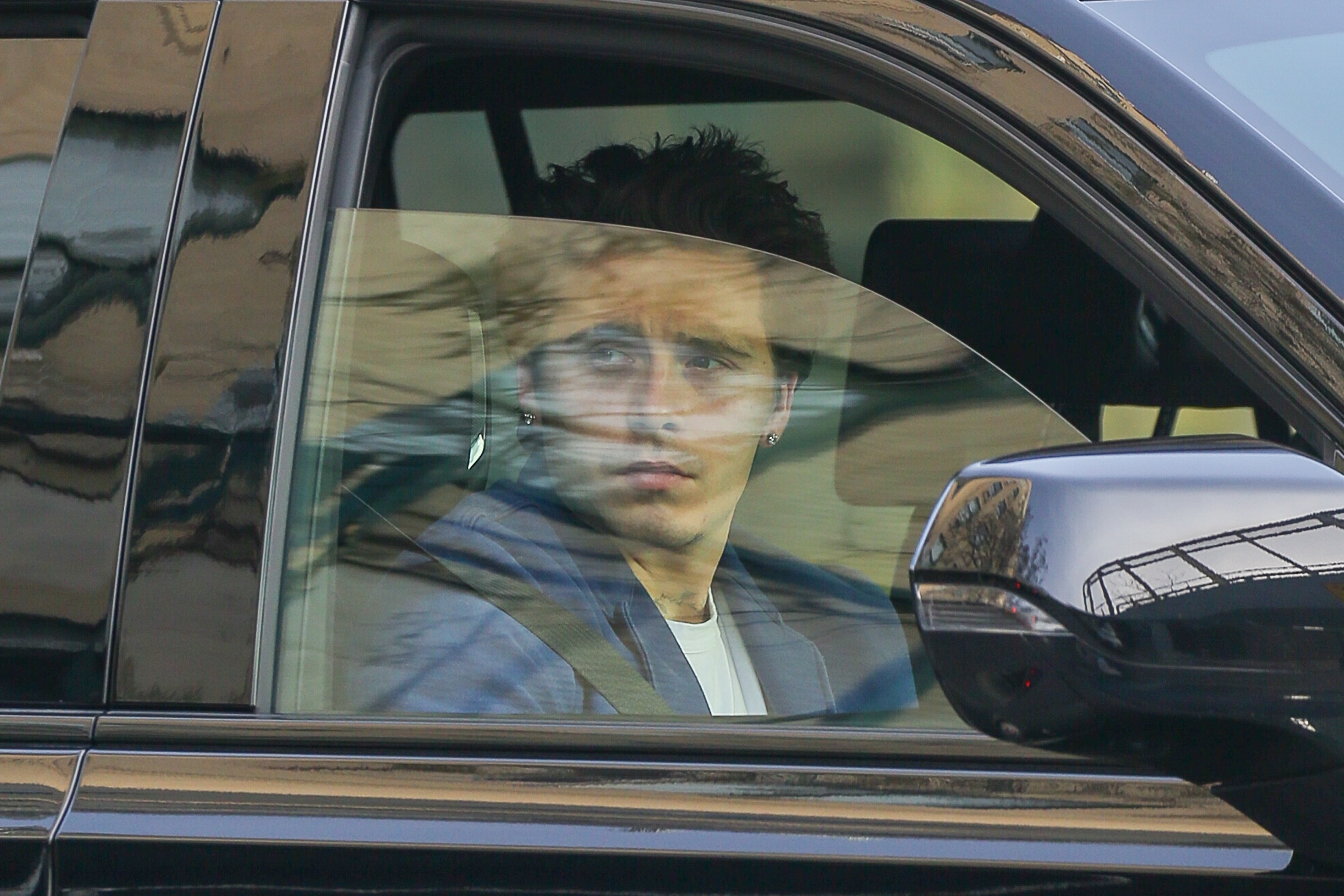 Brooklyn Beckham seated in a car, looking out the window with a contemplative expression