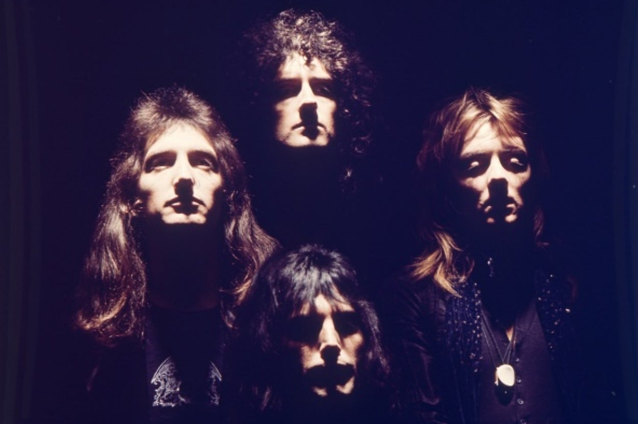 Four people in dramatic lighting, with heads tilted upwards. Each person has distinct hairstyles, creating an iconic visual composition