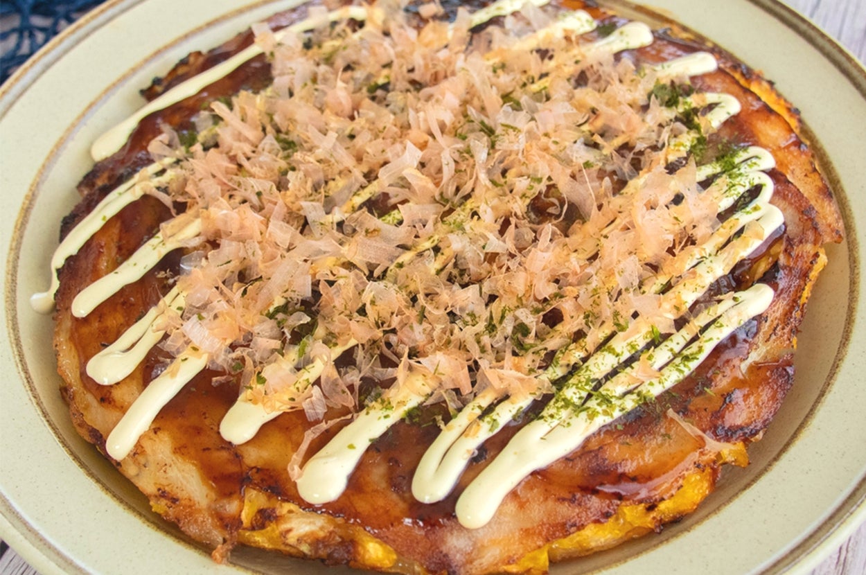 皿に盛られたお好み焼き。鰹節、マヨネーズ、青のりがトッピングされた美味しそうな料理。