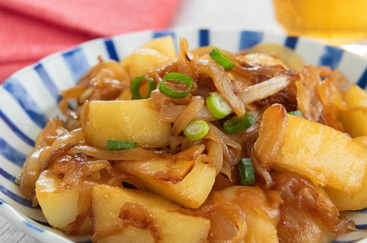 じゃがいもと玉ねぎのめんつゆバター炒めが皿に盛られている。小ネギがトッピングされている。