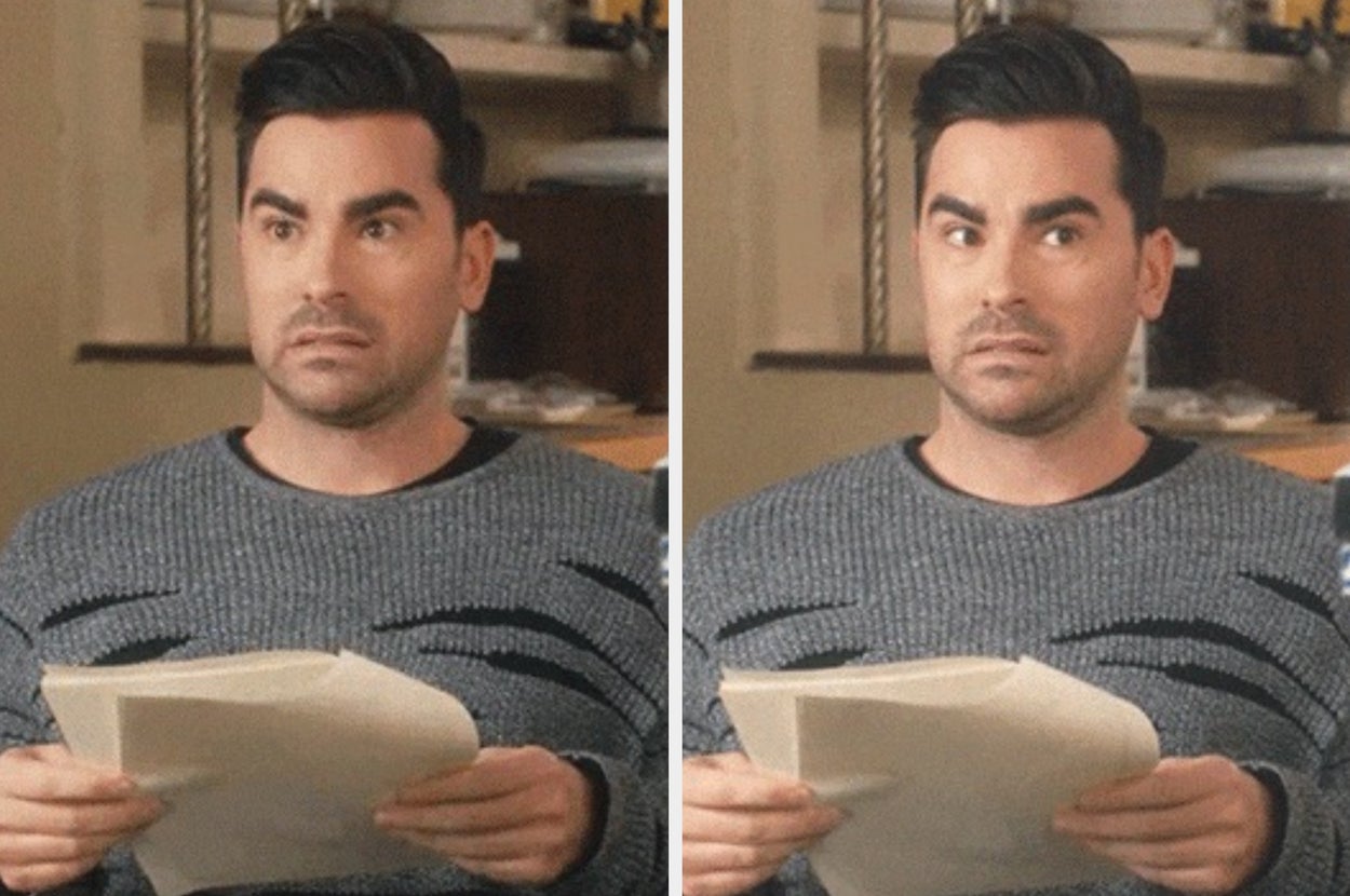 A confused person holding papers, with a surprised expression, in a casual indoor setting