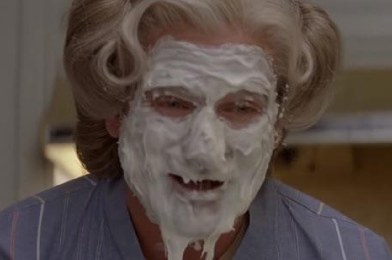 Person with white foam covering face, styled gray hair, wearing a striped shirt