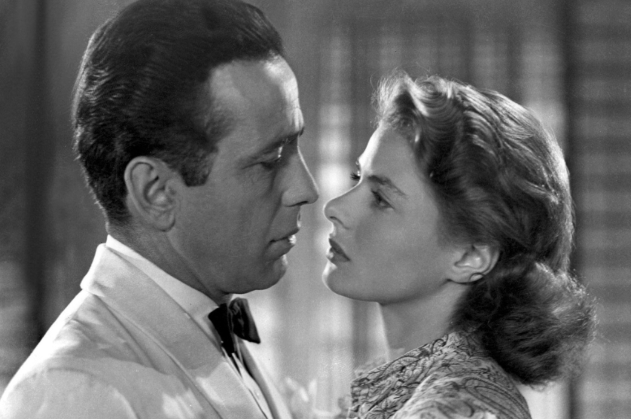 A classic film scene with a man in a tuxedo and a woman in patterned attire, gazing intensely at each other