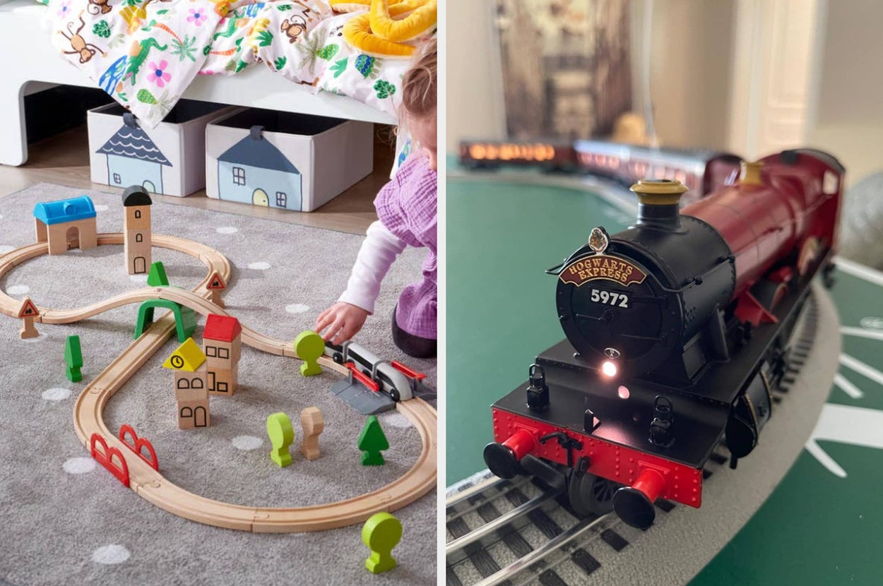 Child playing with wooden train set next to a toy train on a track beside a Christmas tree