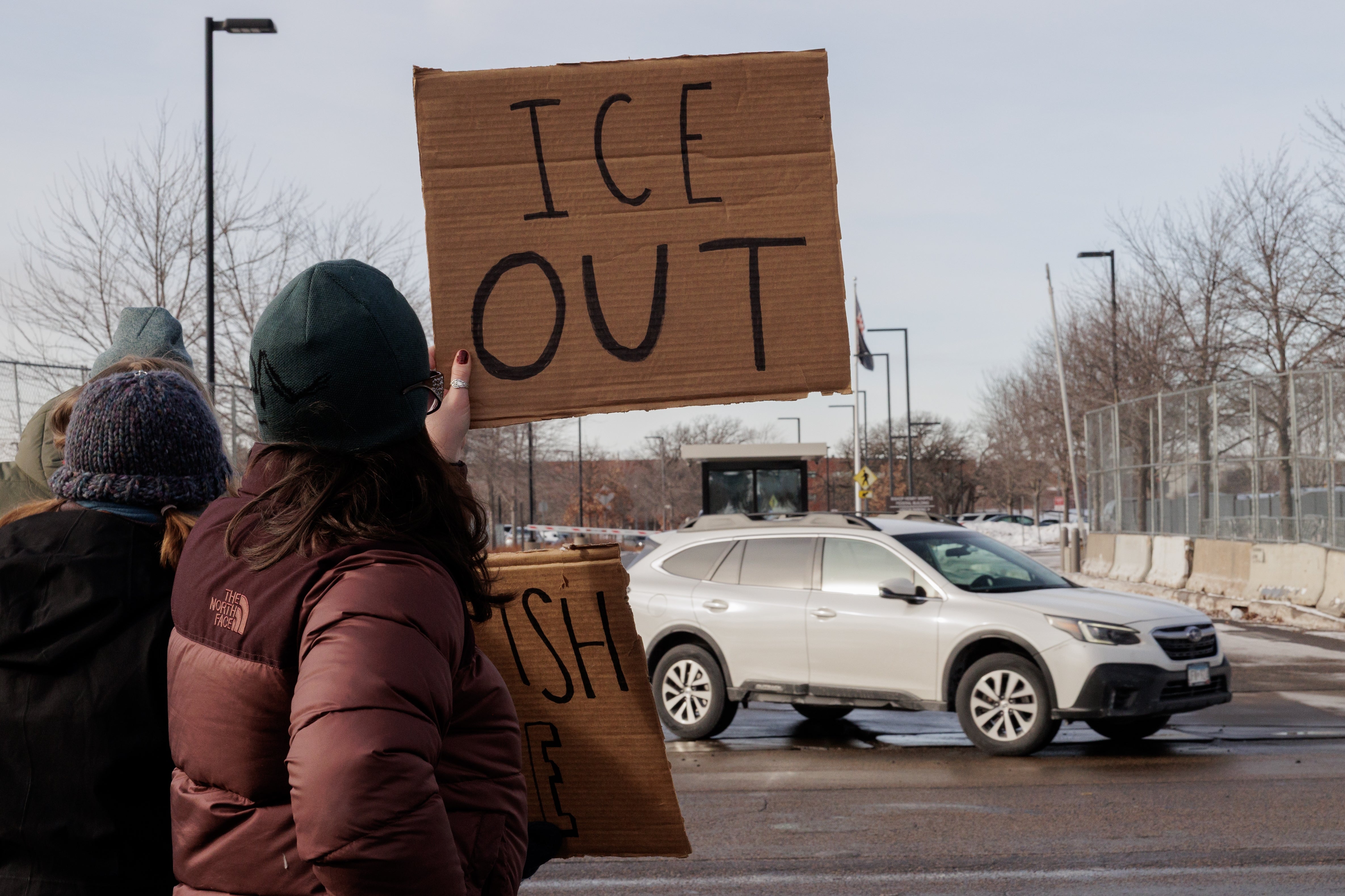 Folk som holder pappskilt under en gateprotest, på ett skilt står det «ICE OUT».