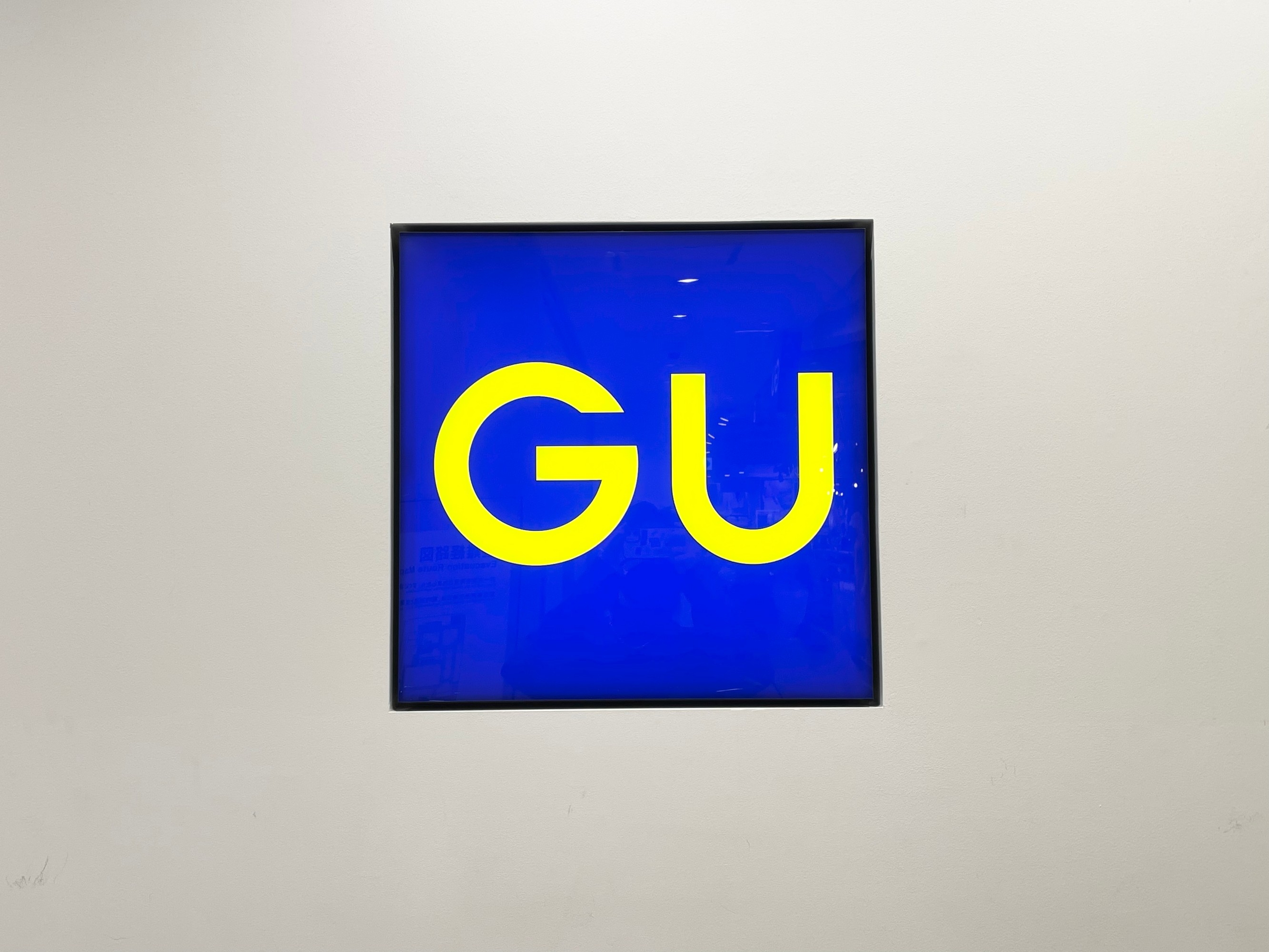 Sign displaying "GU" in bold letters against a plain background