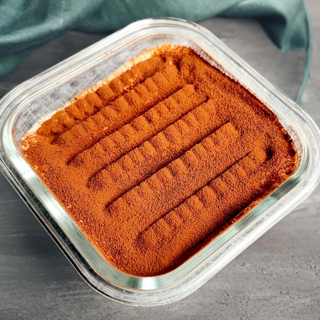 ガラス容器に入ったティラミス、上面にはココアパウダーが振りかけられ、整然とした模様が見える。