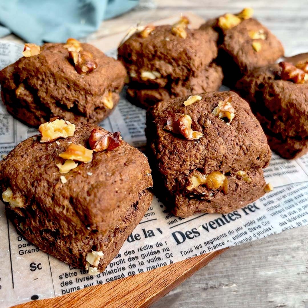 くるみがトッピングされたチョコレートスコーンが新聞紙の上に並んでいます。