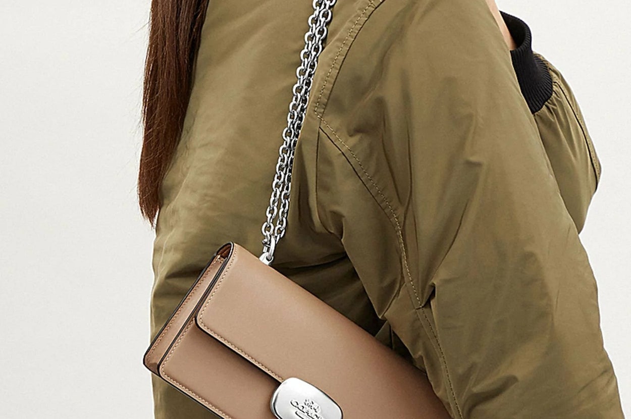 女性がチェーン付きハンドバッグを肩にかけ、カジュアルなジャケットを着ている。バッグはシンプルでエレガントなデザイン。