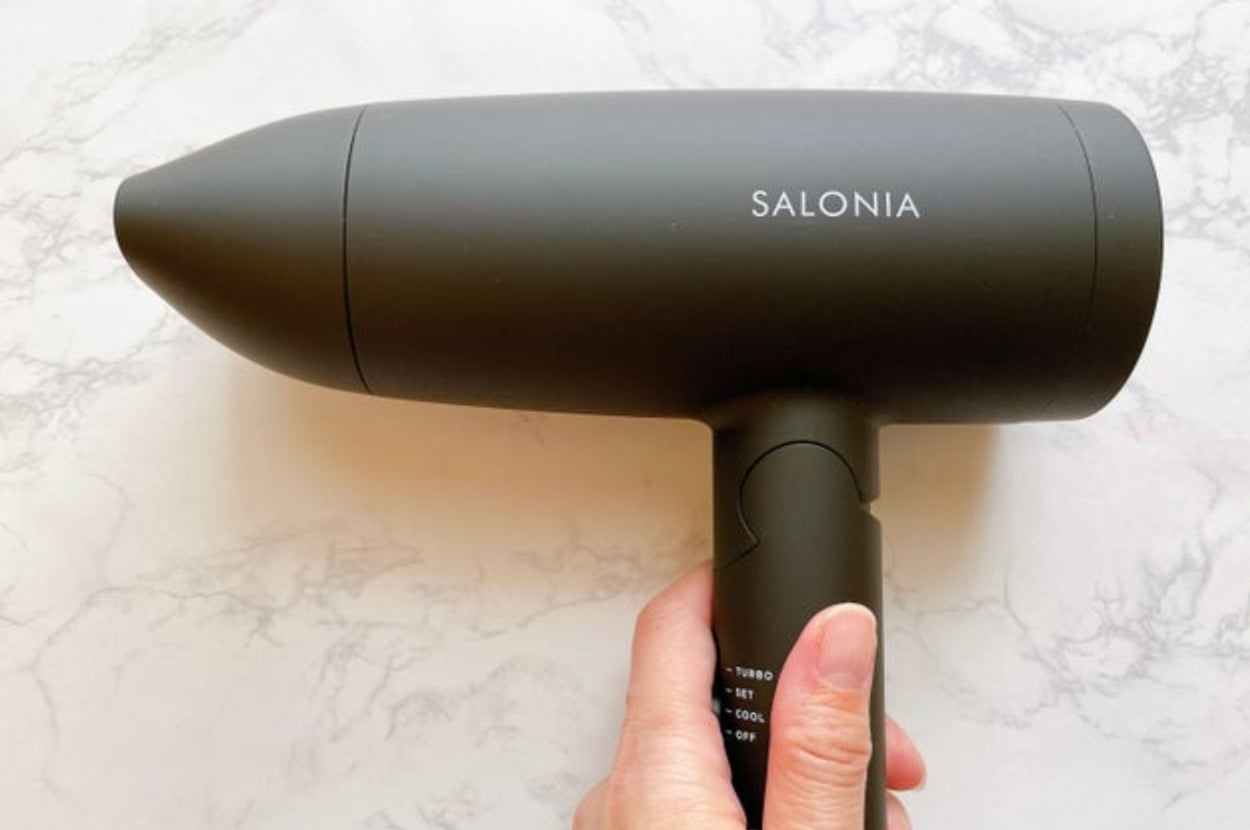 手に持たれたSALONIA（サロニア）のヘアドライヤー。
