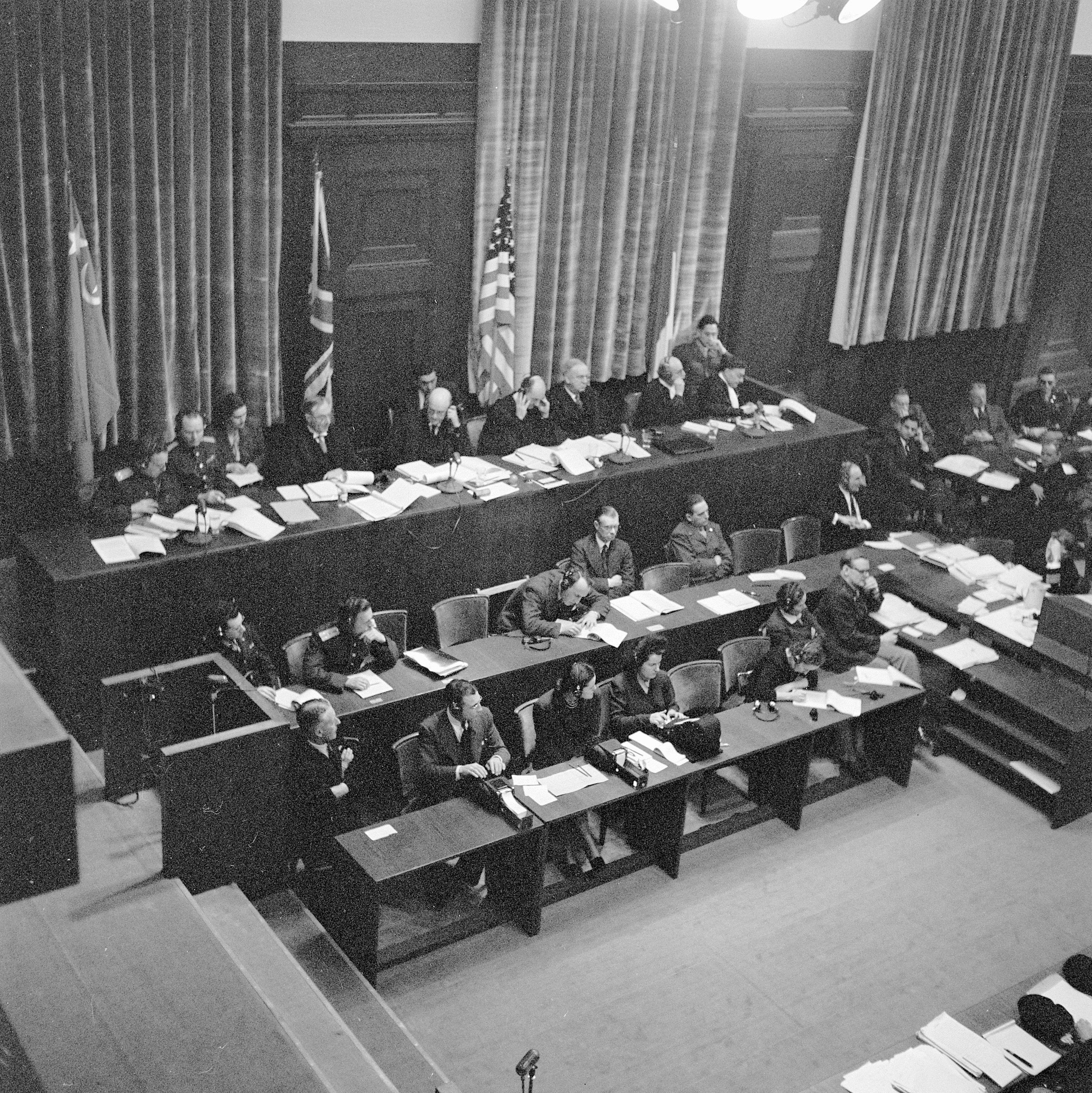 Folk som sitter i en rettssallignende setting med flagg fra forskjellige land, muligens fra en historisk eller betydelig politisk begivenhet