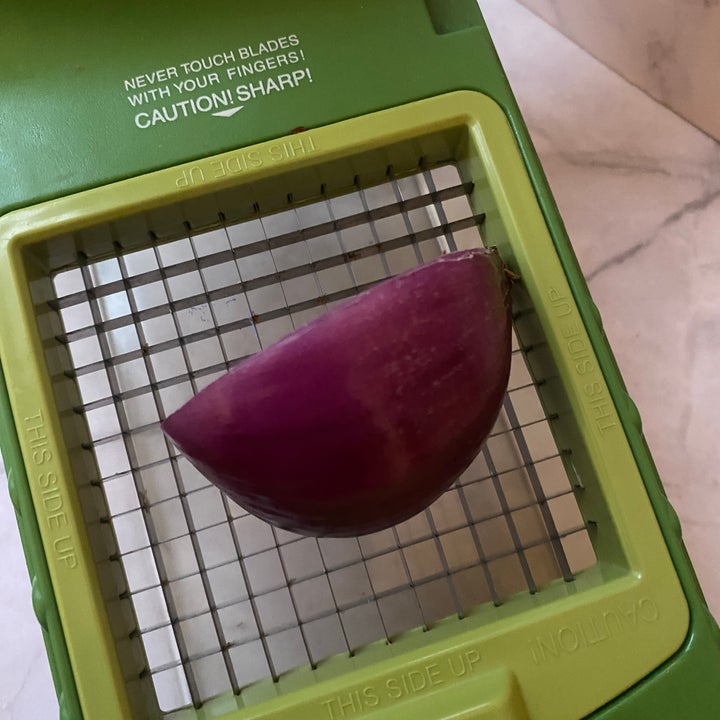Half an onion placed in a kitchen vegetable slicer, ready to be chopped