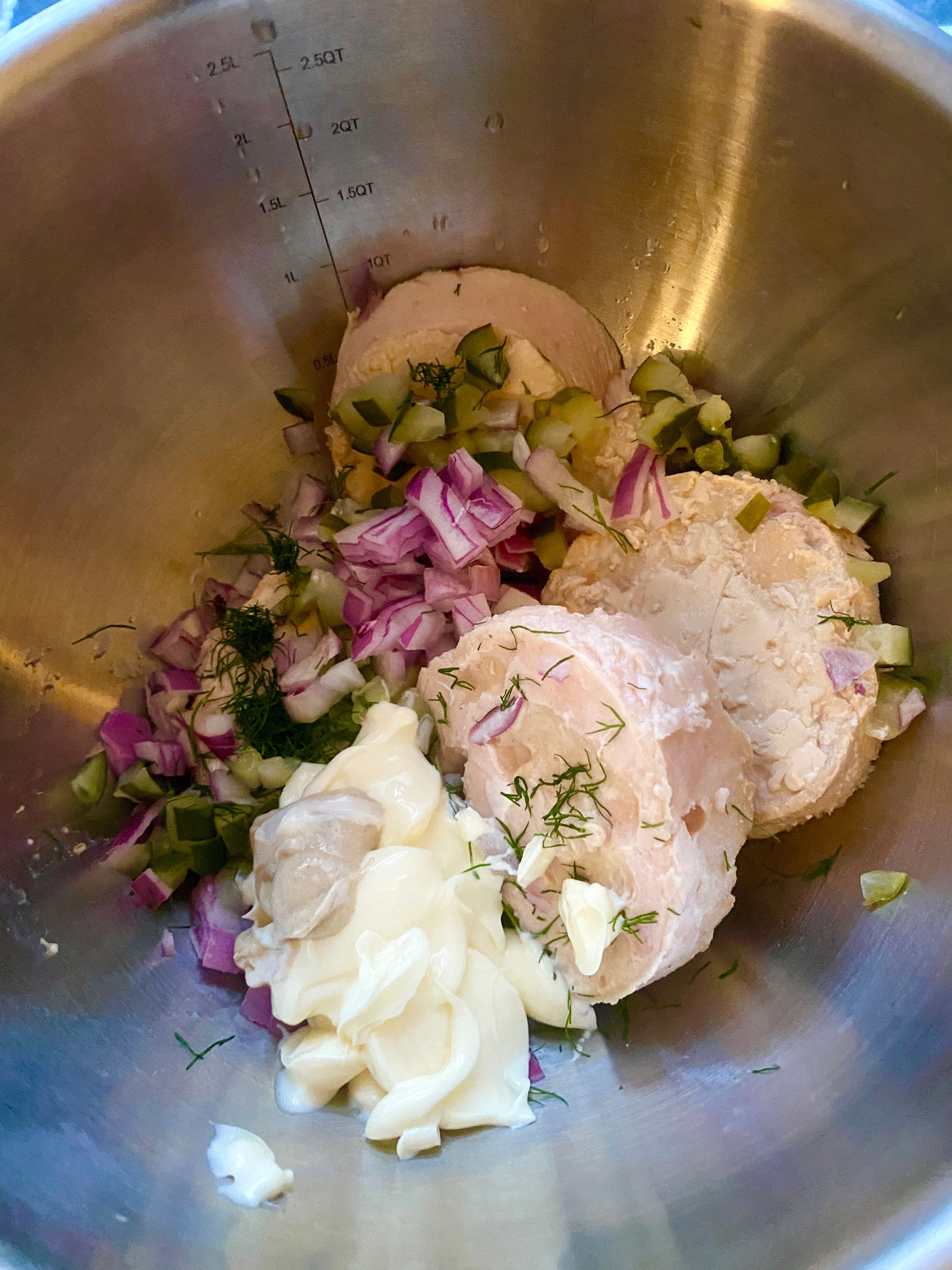 Ingredients in a mixing bowl: chopped red onions, pickles, mayonnaise, and dill