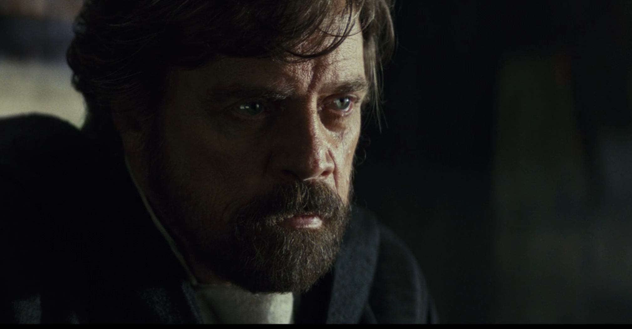 Bearded man in thoughtful expression, wearing a cloak resembling fantasy or sci-fi attire