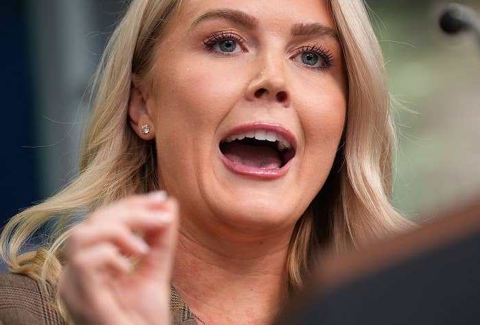 A woman speaks passionately at a microphone, gesturing with her hand during an event