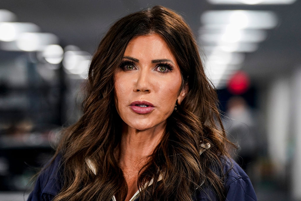 I'm not sure who this is, but the person has long hair and is wearing a jacket, appearing to speak or be in a public setting