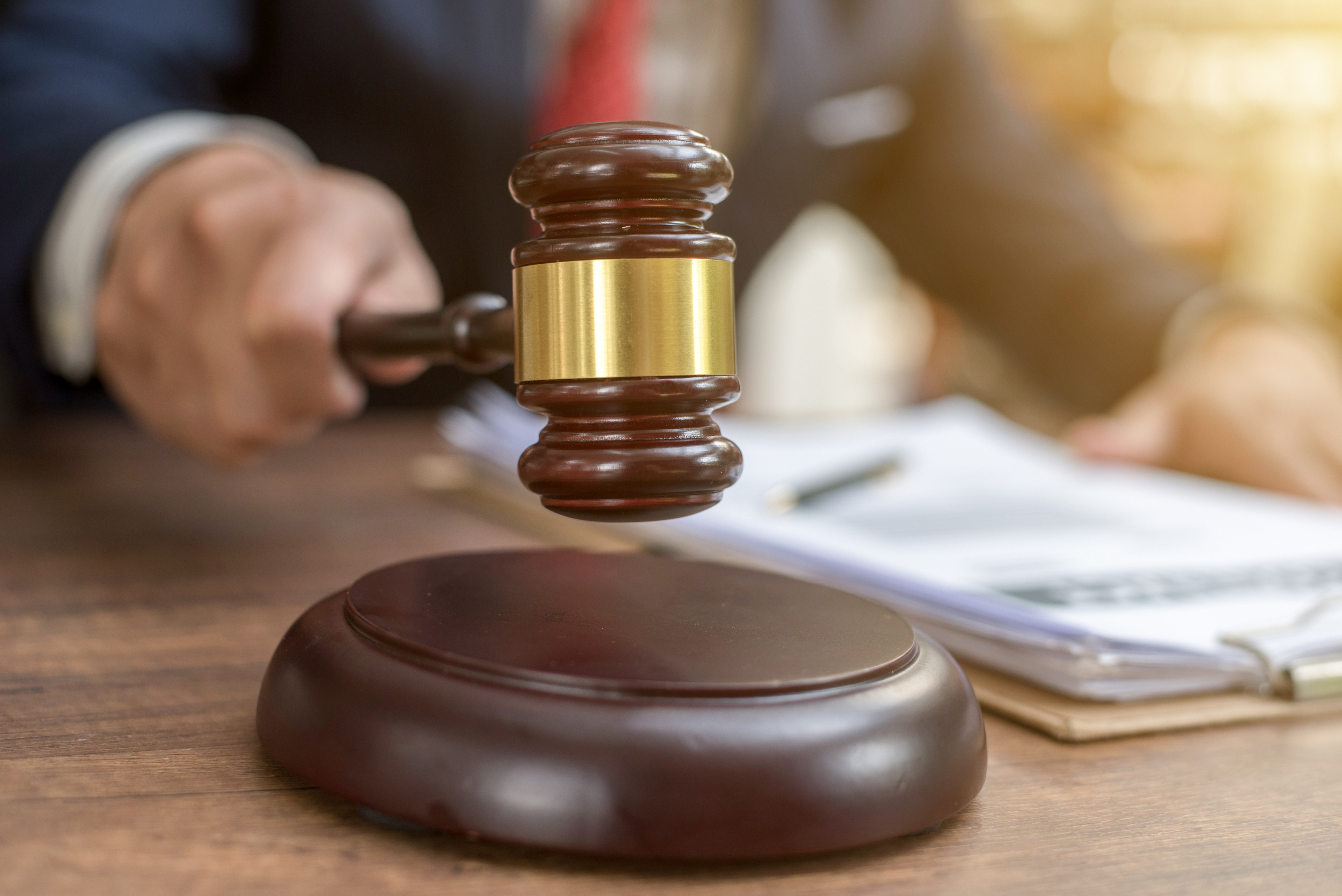En dommers hånd som holder en klubbe klar til å slå, symboliserer en juridisk avgjørelse i en jobb- og pengesammenheng