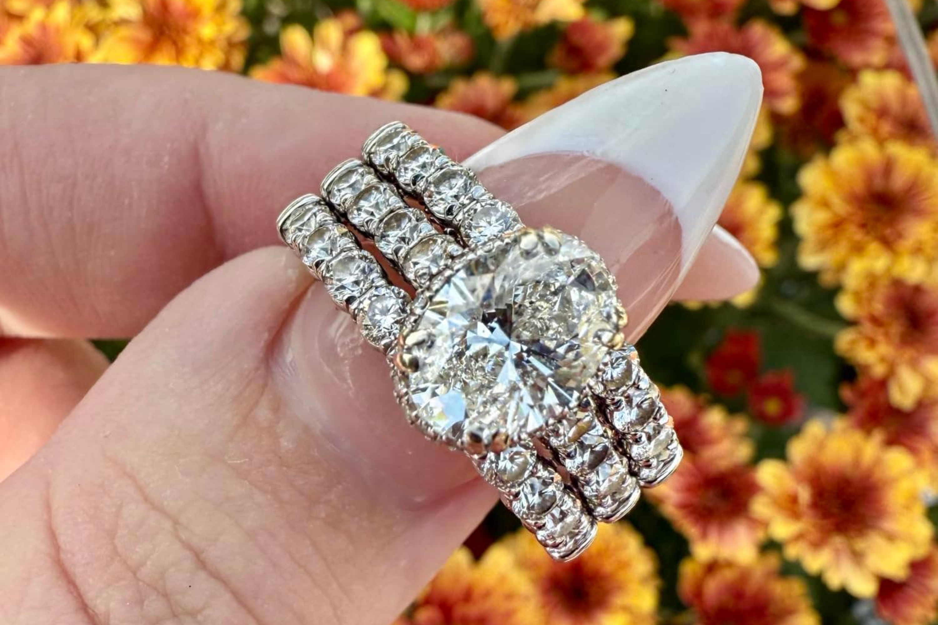 closeup of reviewer holding a sparkling diamond ring against a bunch of flowers