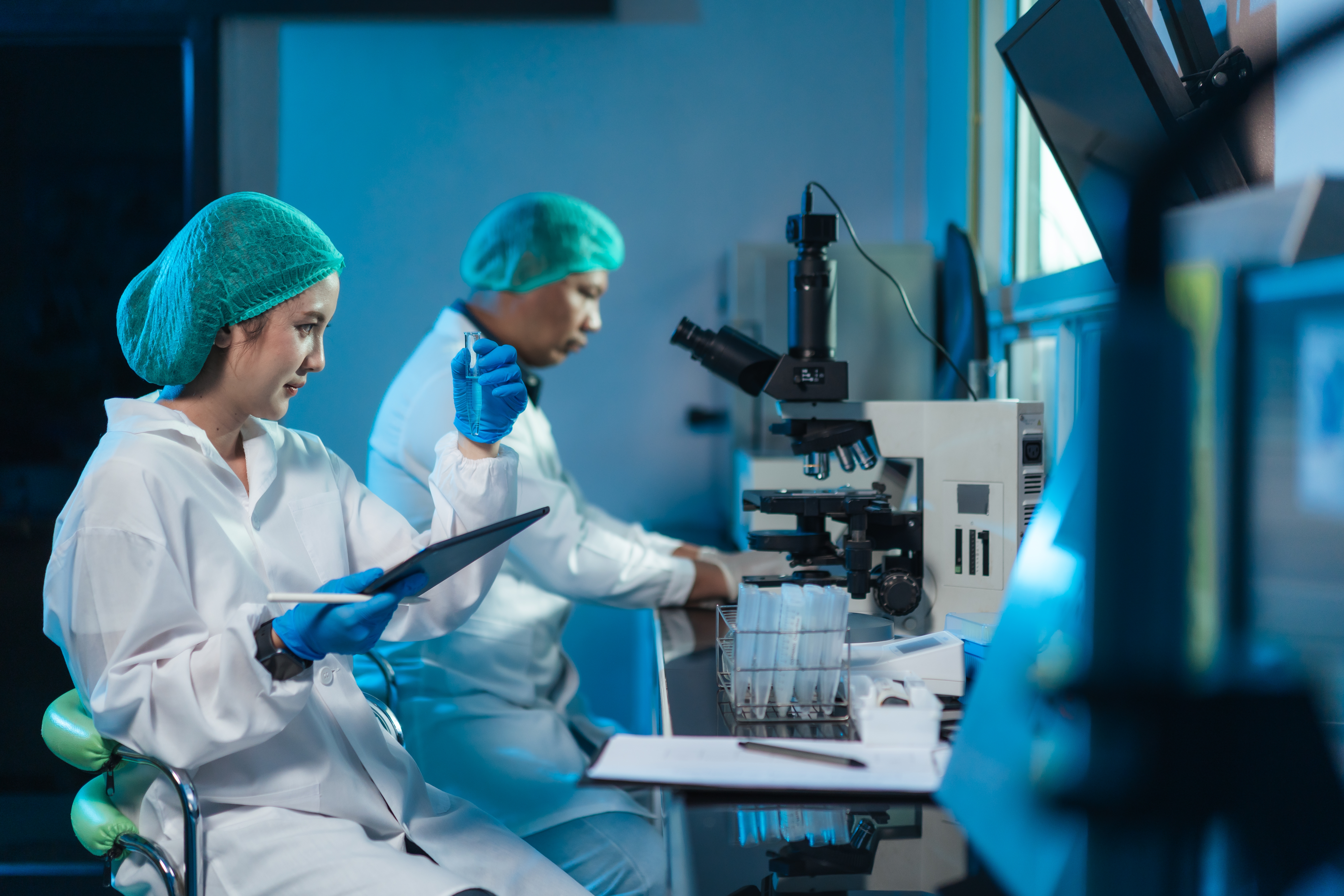 People successful laboratory coats and protective cogwheel enactment with microscopes successful a laboratory setting