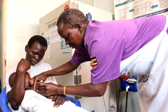 Healthcare idiosyncratic    administering a vaccine to a kid  held by a parent. A aesculapian  fridge and informational poster are successful  the background