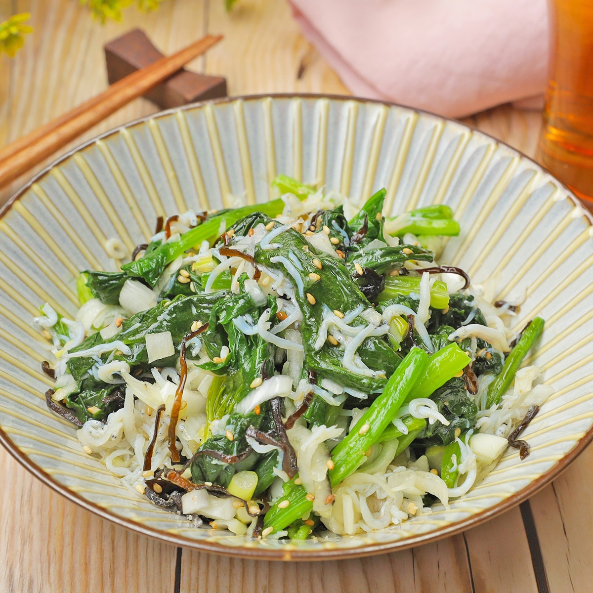 皿に盛られた新鮮な野菜サラダ。シラス、ゴマ、刻み野菜がトッピングされている。テーブルには箸が置かれている。