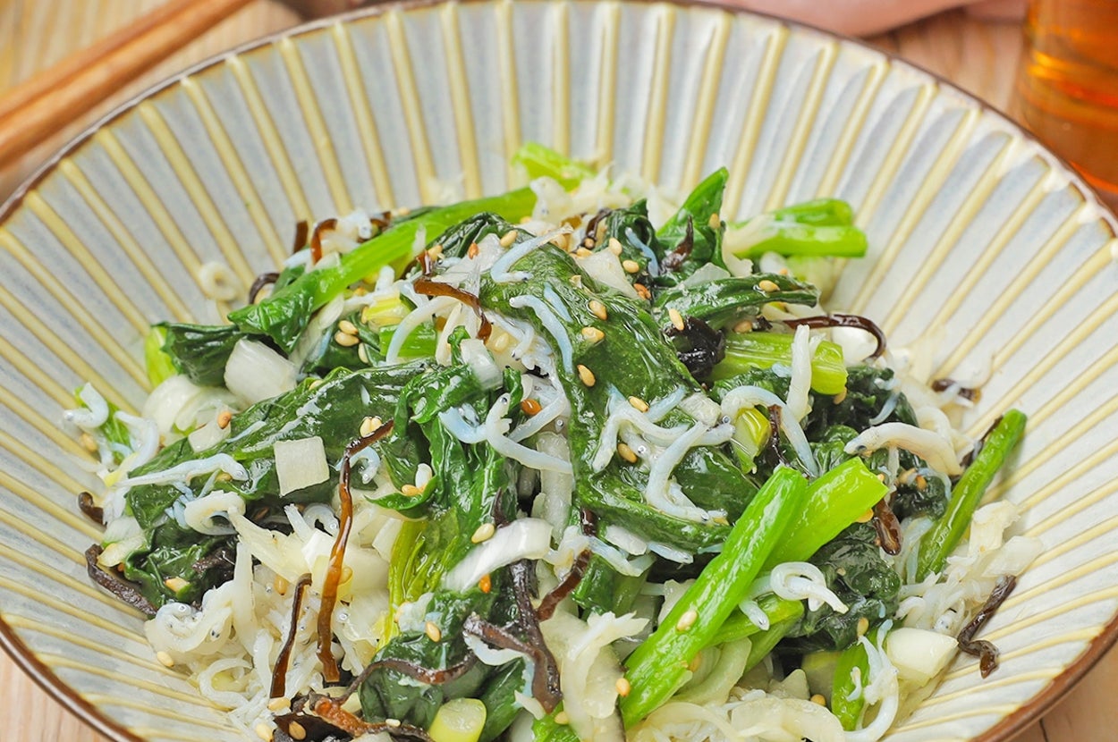 皿に盛られた新鮮な野菜サラダ。シラス、ゴマ、刻み野菜がトッピングされている。テーブルには箸が置かれている。