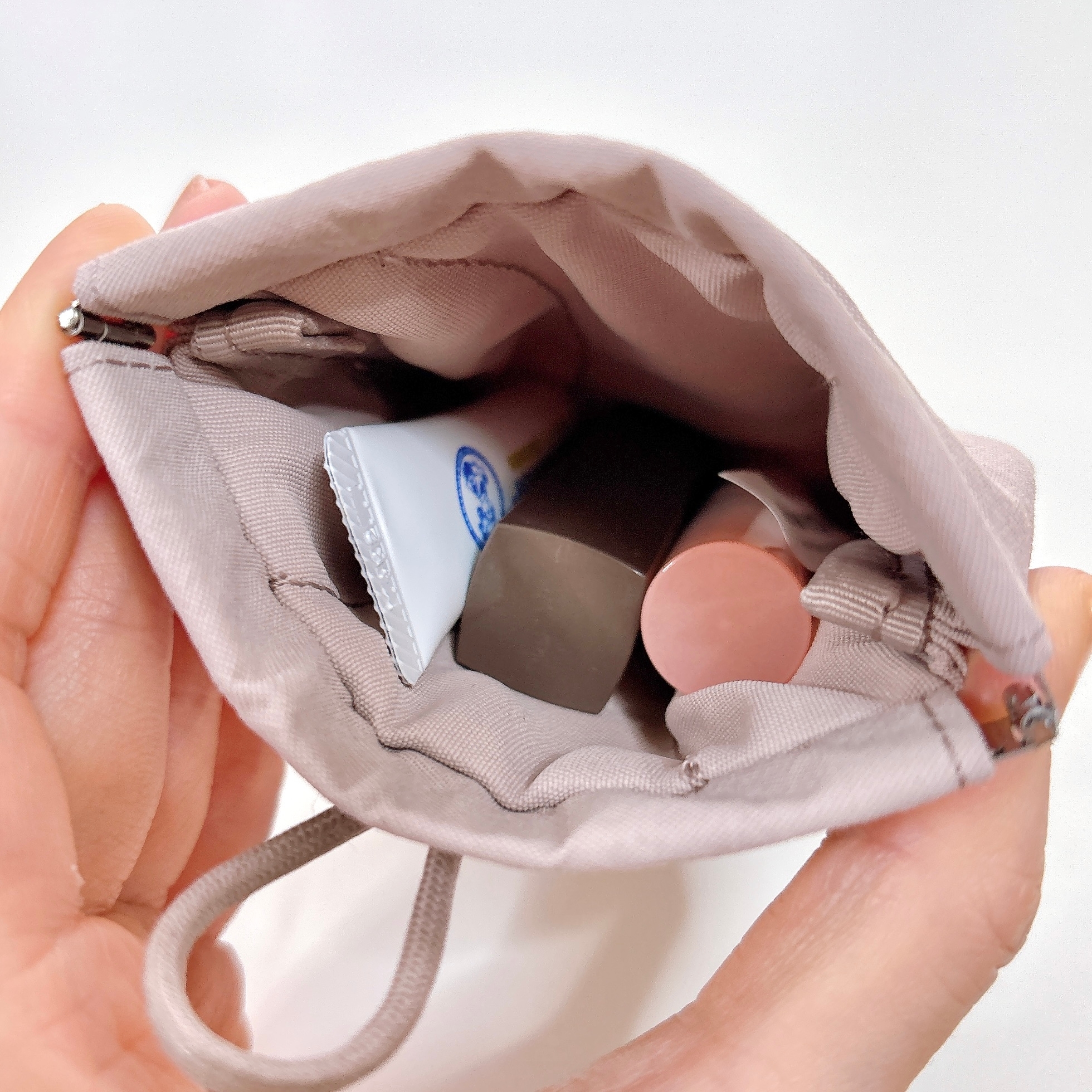 無印良品の「リンクルナイロン 片手で開くフラットポーチ」ばね口を片手で押し開けた様子