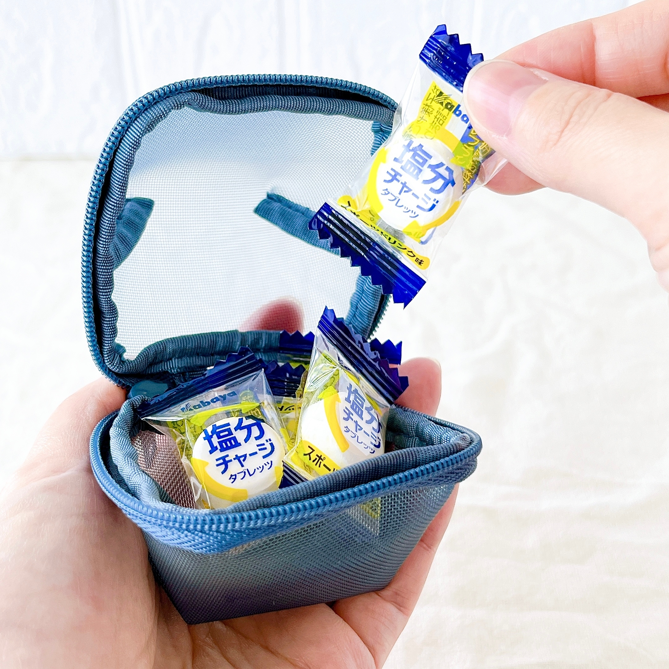 無印良品の「ナイロンメッシュ コンパクトポーチ」中に入った塩分チャージタブレットを人が取り出そうとしている様子