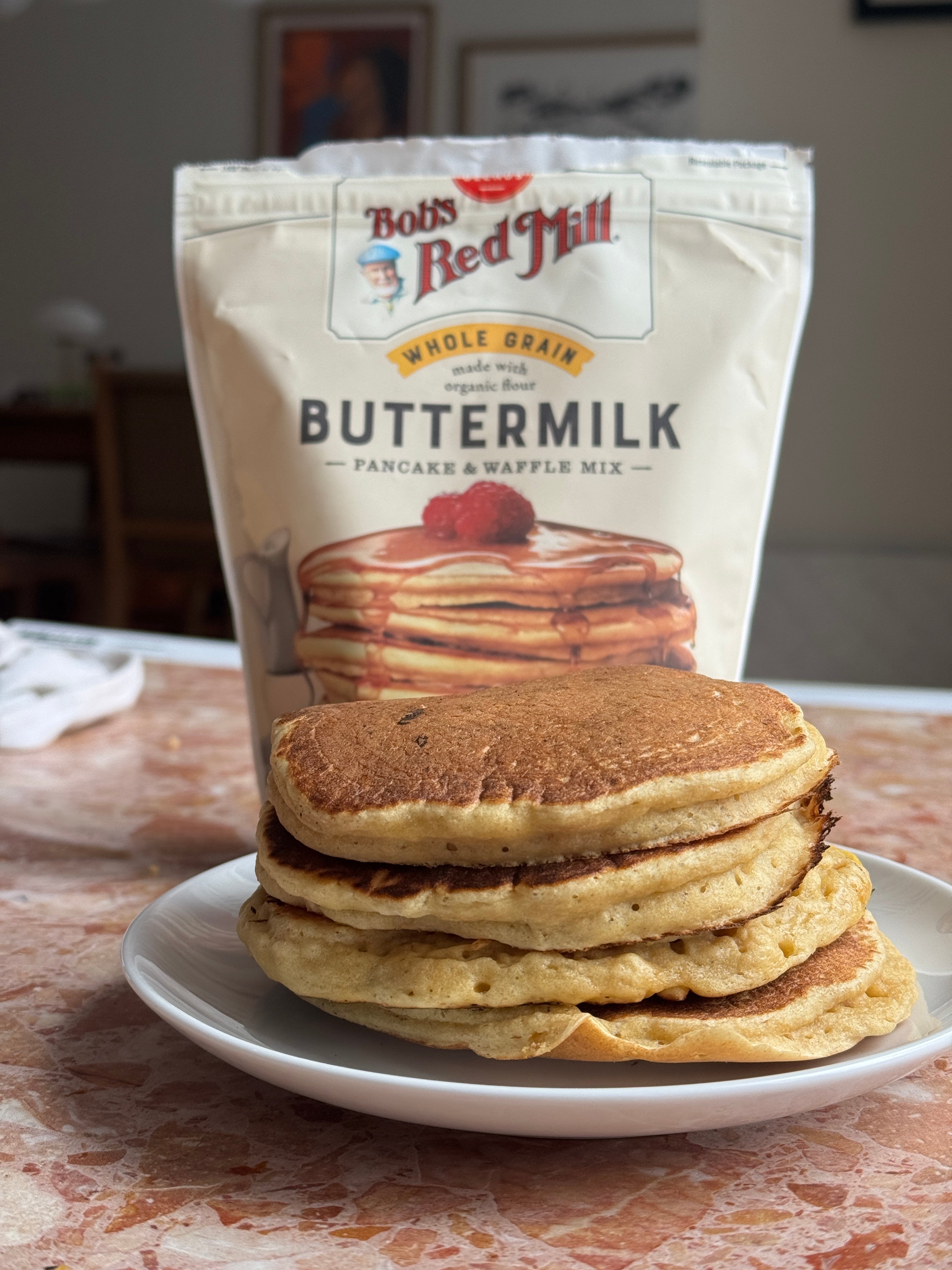 Pancakes stacked on a plate in front of a bag labeled "Bob's Red Mill Buttermilk Pancake &amp;amp; Waffle Mix."