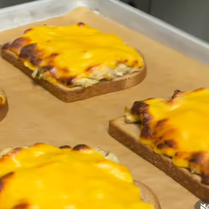 Toasted bread topped with melted cheese on a baking sheet