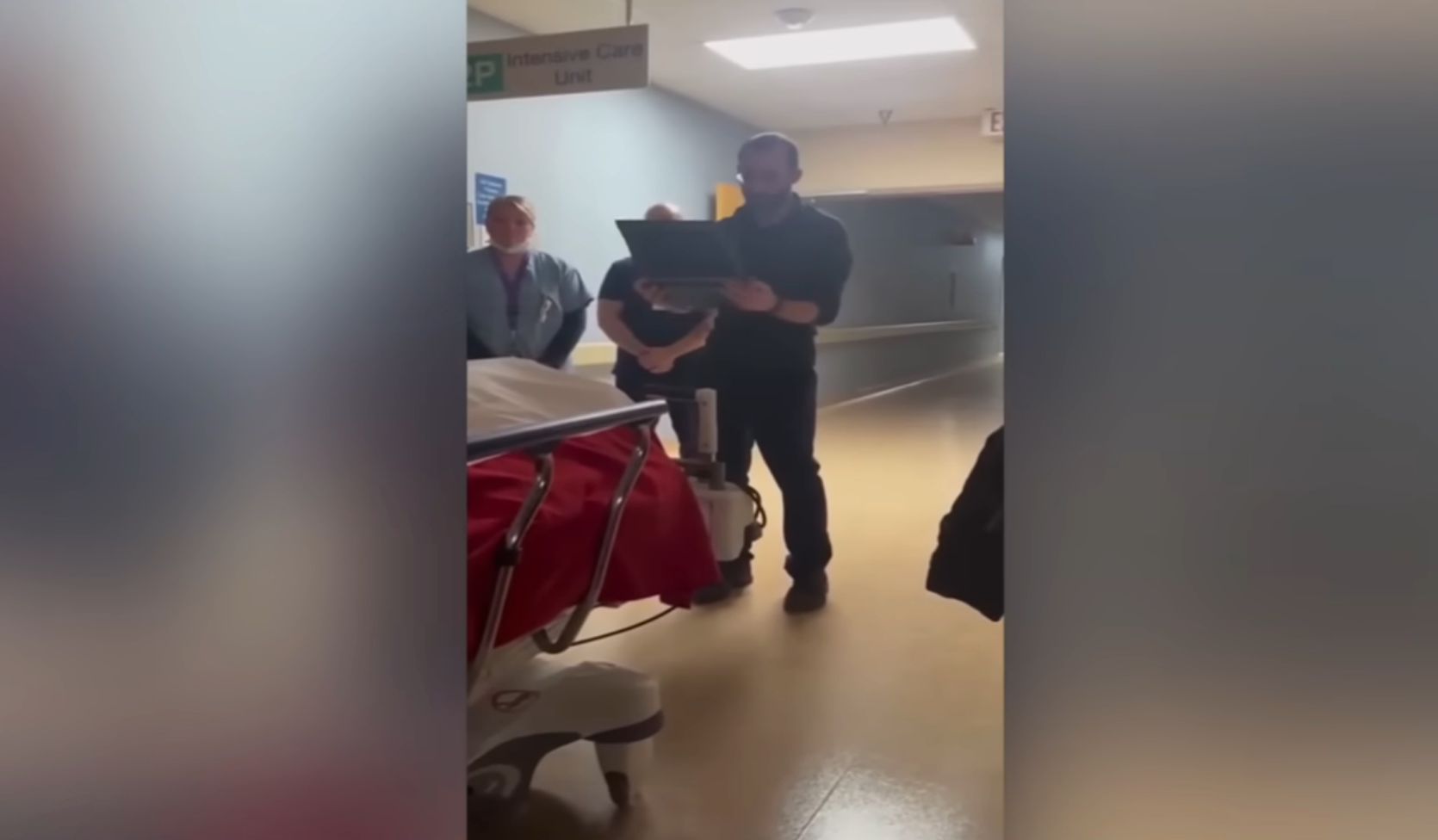 Person som står ved siden av en sykehusseng og har sertifikat med medisinsk personell i nærheten i en sykehusgang