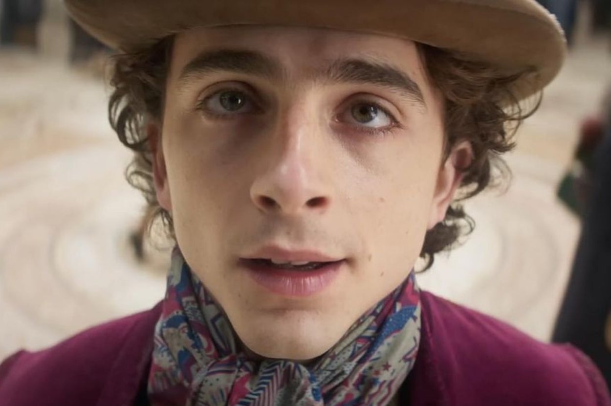 A person with expressive eyes wears a patterned scarf and hat, appearing curious or contemplative