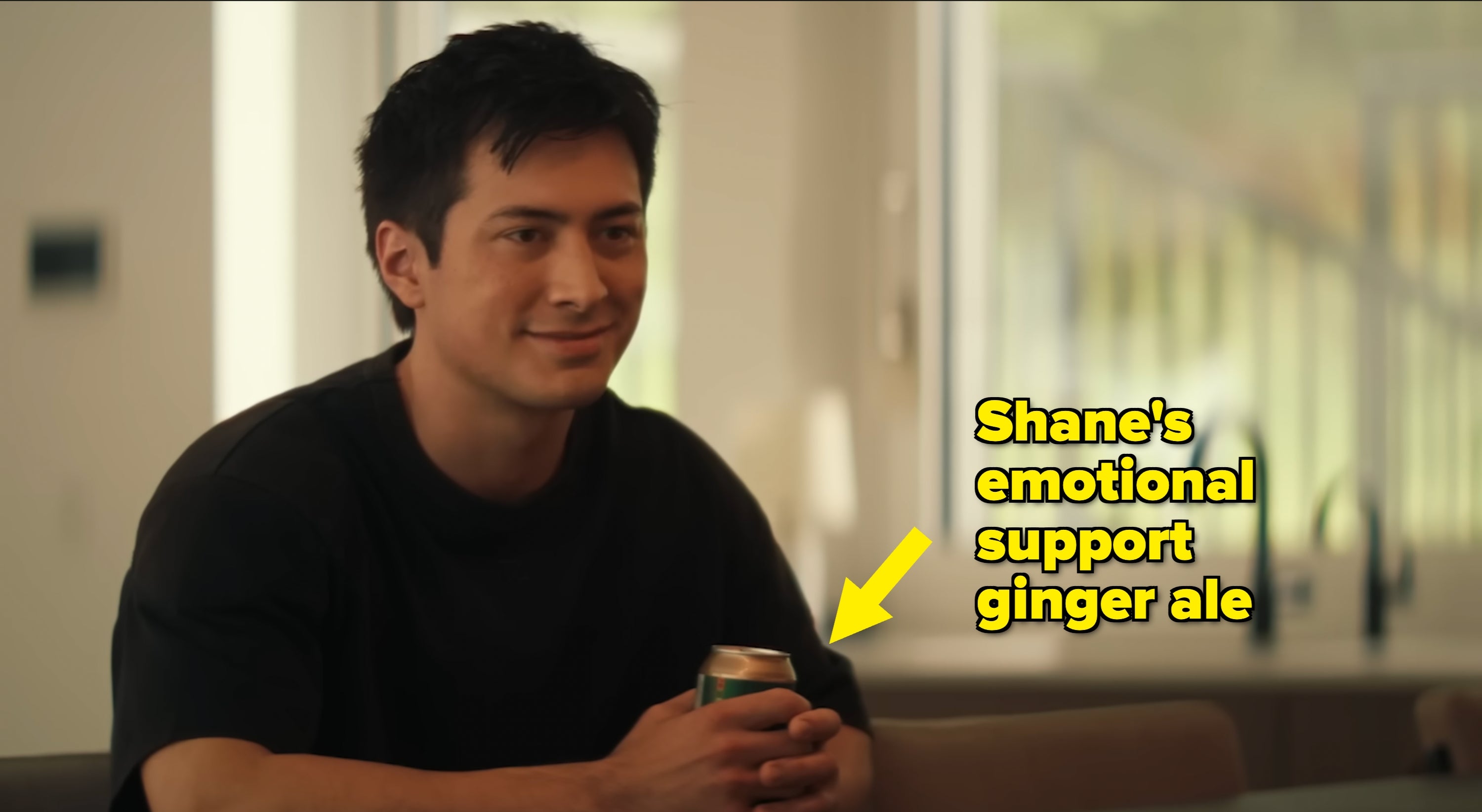 A person smiling while sitting indoors, holding a can in both hands