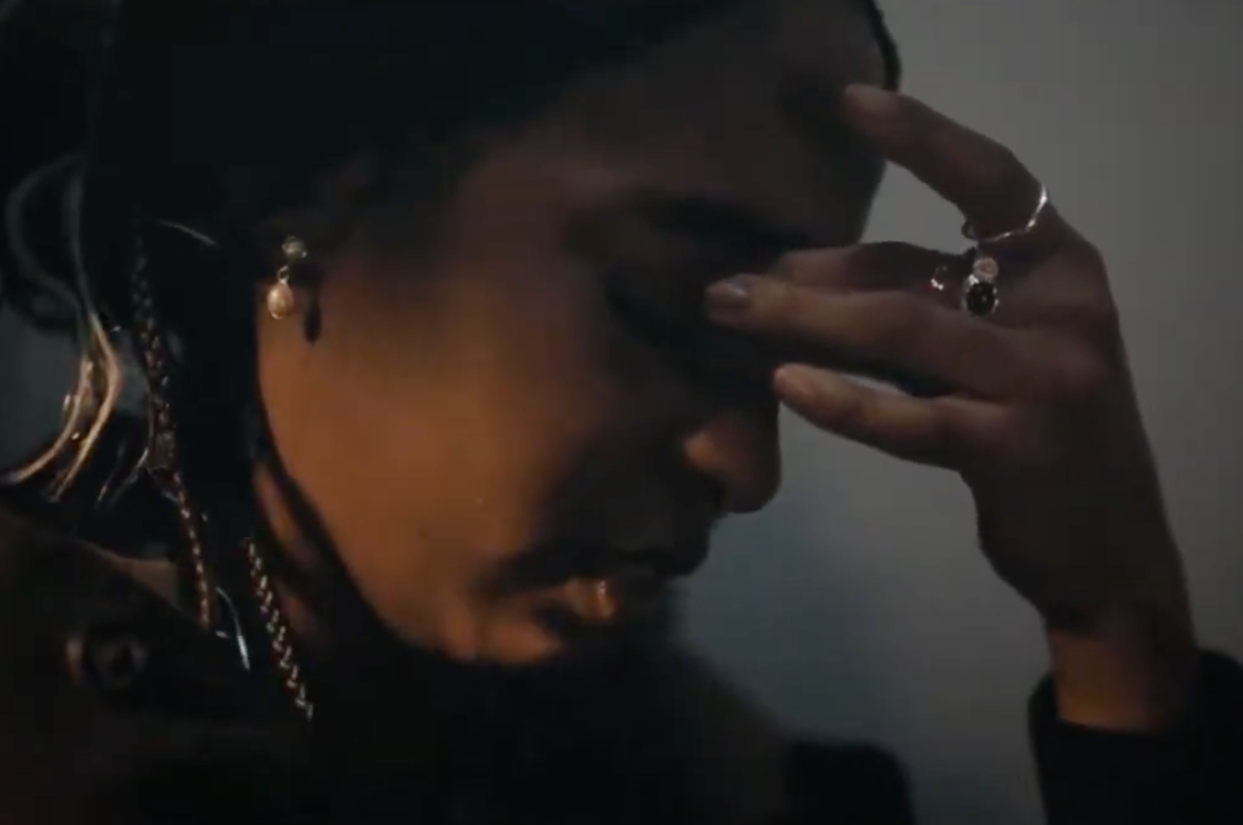 Person with closed eyes and hand on forehead, wearing earrings and rings, conveying a thoughtful or emotional moment