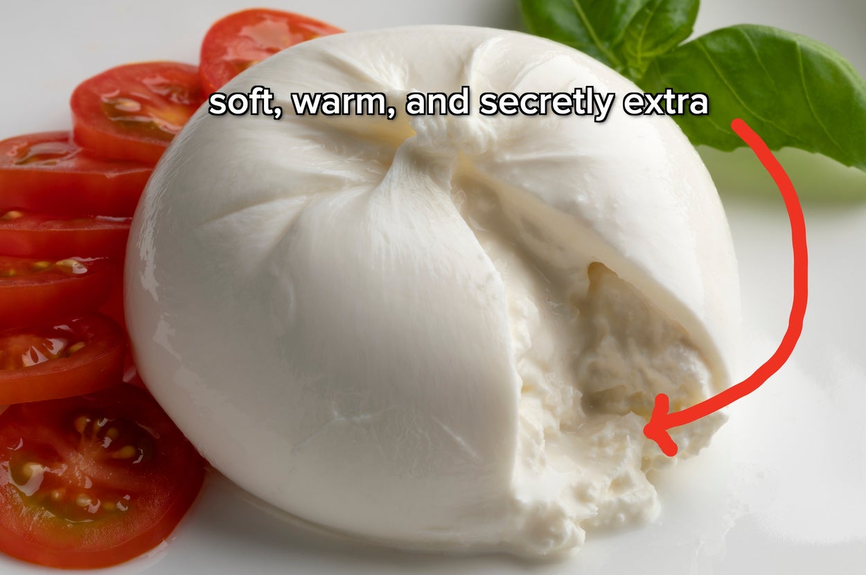 Close-up of creamy burrata cheese, partially opened, with sliced tomatoes and basil in background. Text reads: "soft, warm, and secretly extra."