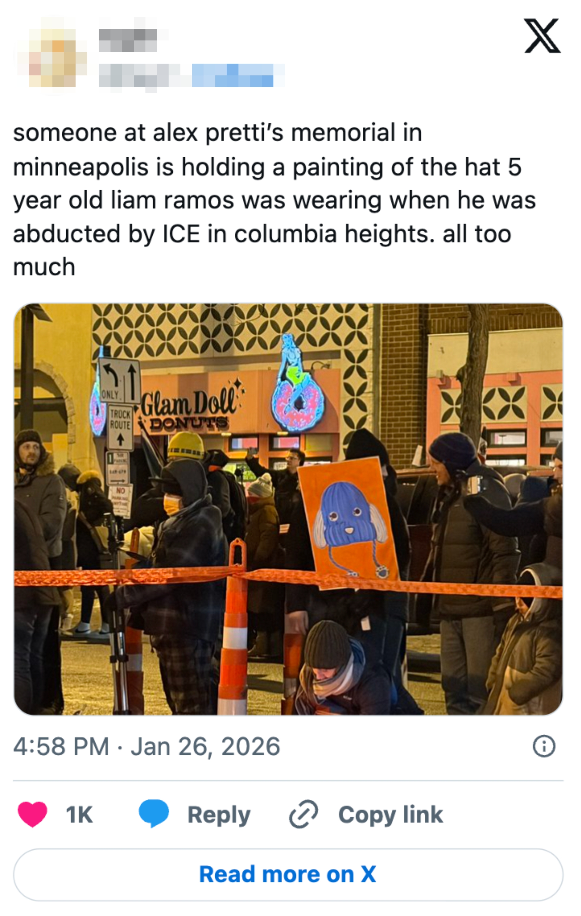 En gruppe mennesker ved et minnesmerke i Minneapolis. En person holder et barns maleri av en blå karakter. Bakgrunnen inkluderer en smultringbutikk