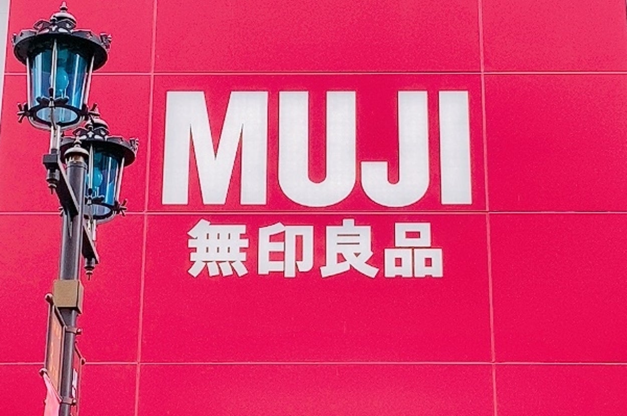 無印良品の看板が掛かった店舗の外観。モダンなデザインの建物と街灯が見えます。