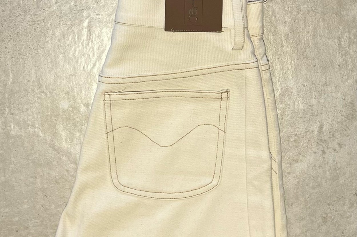折りたたまれたジーンズの一部が写っており、ポケットの縫い目が見えます。ブランドのタグがウエストにあります。
