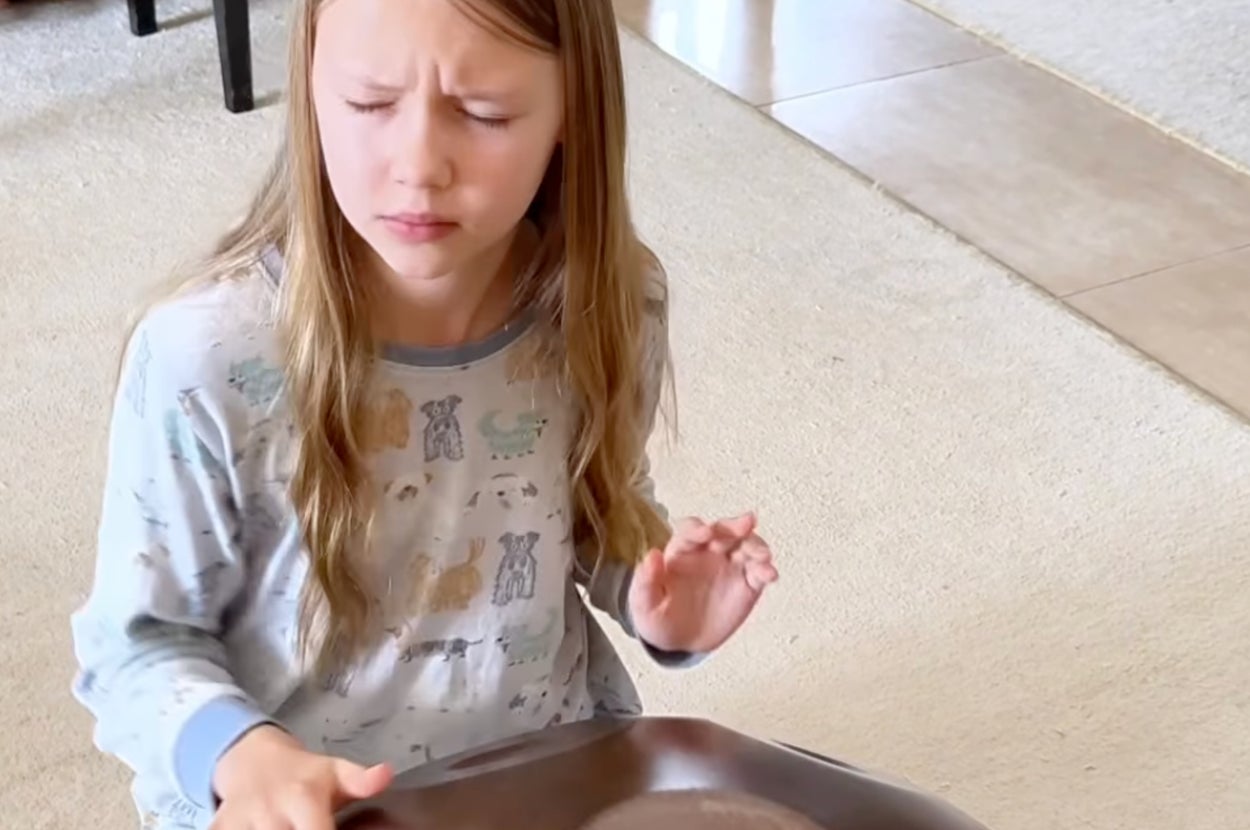 若い女の子がハングドラムを演奏している様子。彼女はくつろいだ表情で、パジャマを着ている。