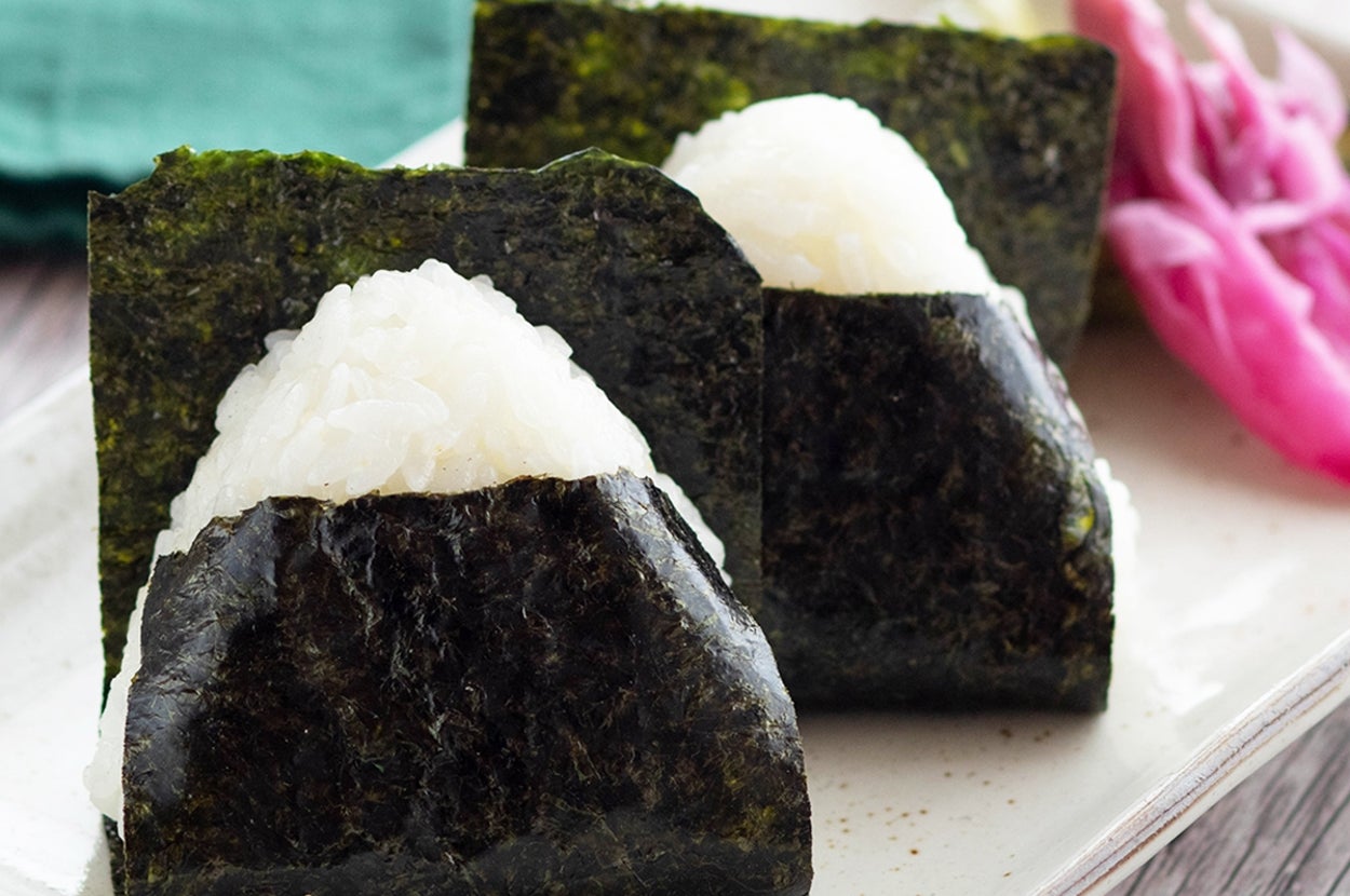 皿にのせられた海苔で巻かれたおにぎり２つ、横に漬物が添えられている。