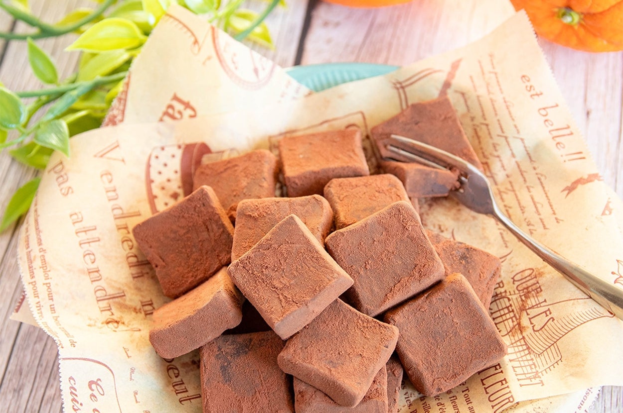 生チョコレートが皿に盛られており、背景にはオレンジと緑の葉が見える。