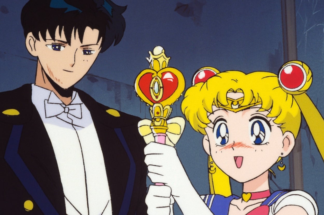 Anime characters, one with a tuxedo, the other with a sailor outfit and heart-shaped wand, look surprised and happy