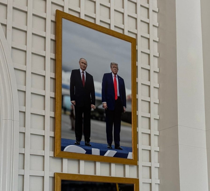 Bilder av to menn, begge iført dress og røde slips, henger på en vegg i utsmykkede gullrammer