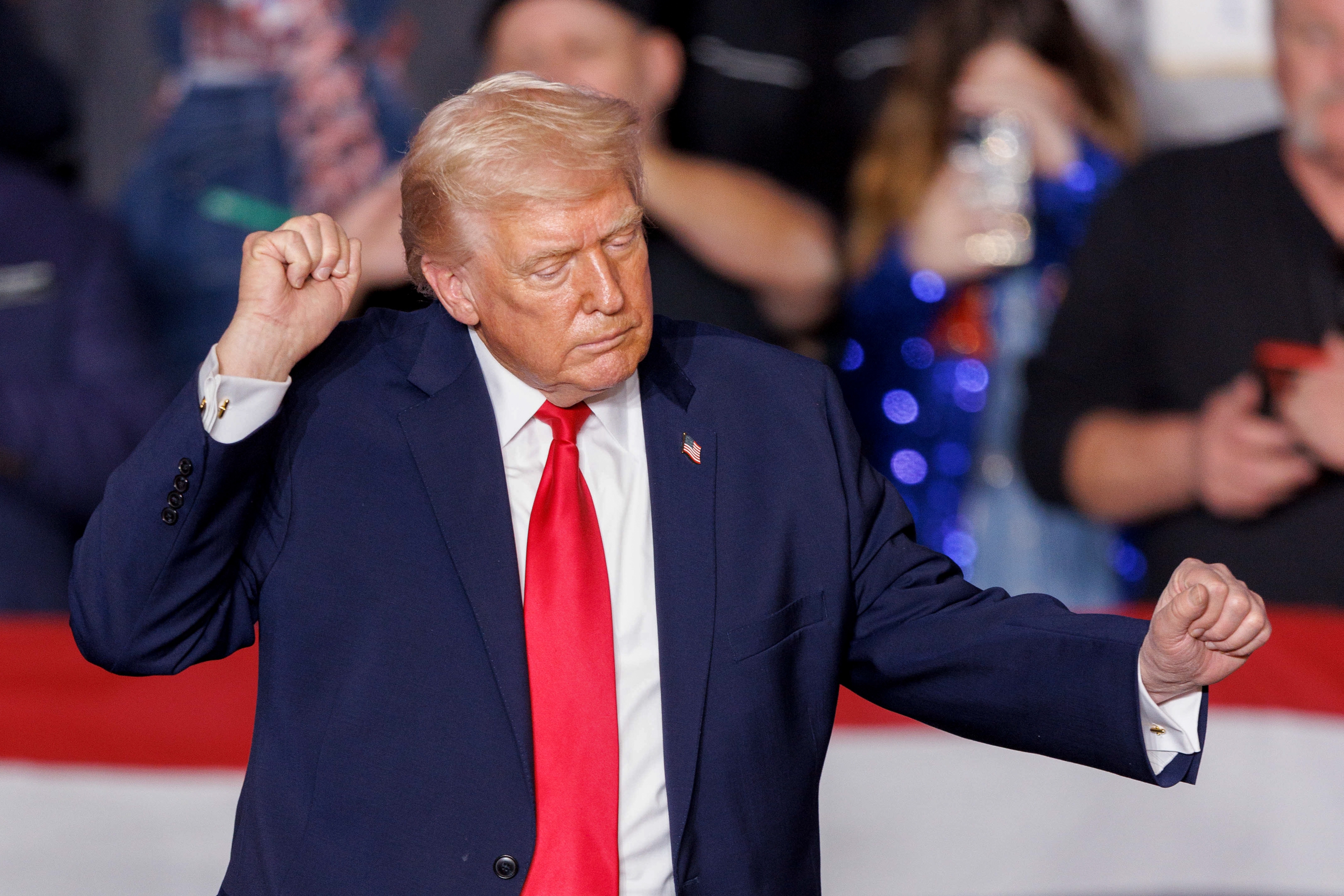 Jeg vet ikke hvem dette er, men bildet viser en mann i dress og rødt slips som gestikulerer med en folkemengde i bakgrunnen