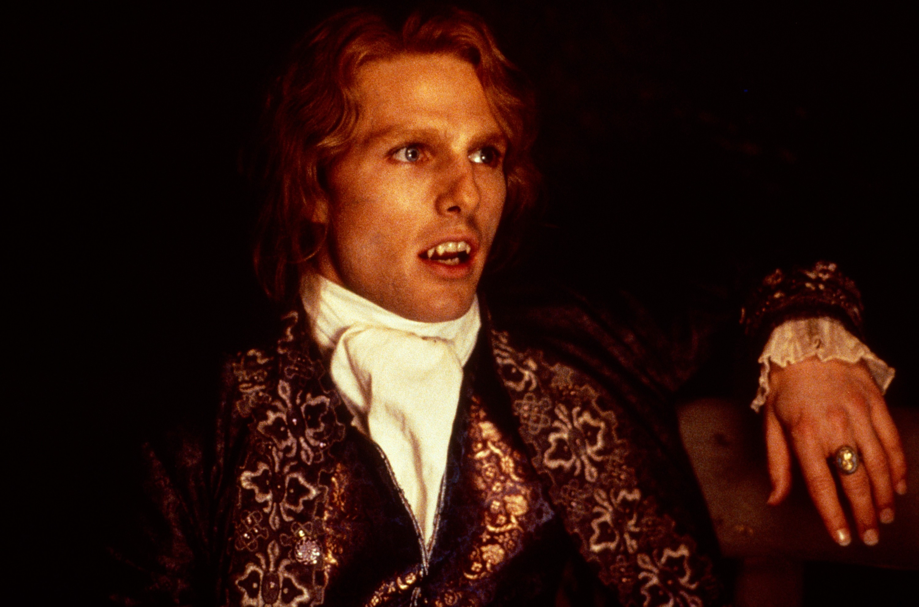 Tom Cruise successful  a vampire costume with ornate covering  and fanged teeth