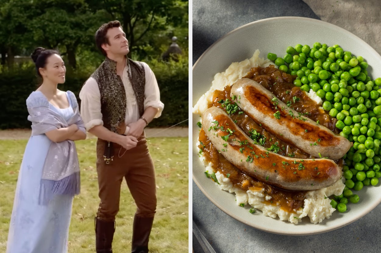 Two people in period costumes outdoors next to a dish of sausages on mashed potatoes with peas