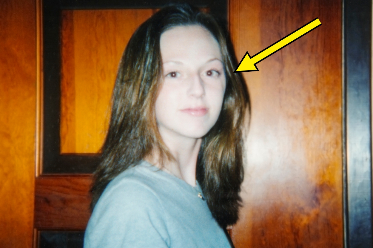 Person looking at the camera indoors with a yellow arrow pointing at them