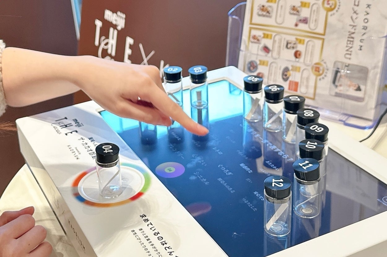 子どもが数字の記載された透明のボトルが並ぶインタラクティブスクリーンを操作している。