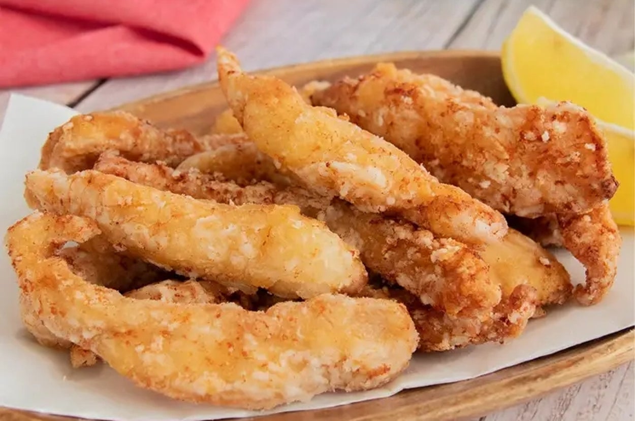 レモンが添えられた鶏肉のフライドチキンが木製の皿に盛られている。